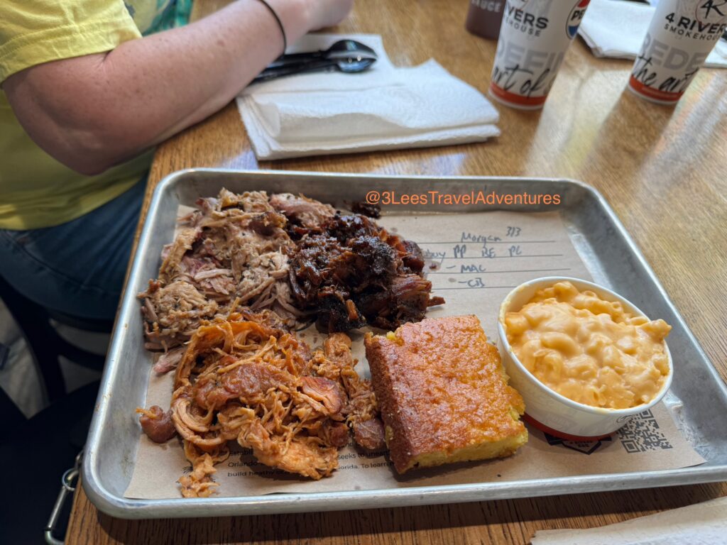 A Delicious Cowboy Combo Platter from 4 Rivers BBQ Smokehouse featuring Pulled Pork, Pulled Chicken, Burnt Ends, Mac and Cheese, and Texas Cornbread.
